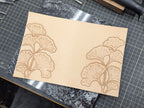Work in progress of tooling ginkgo leaves on a natural leather cover on a quartz slab