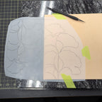 Outline of ginkgo leaves on vellum paper overlaid on natural leather with a tracing stylus on a quartz slab on a cutting mat