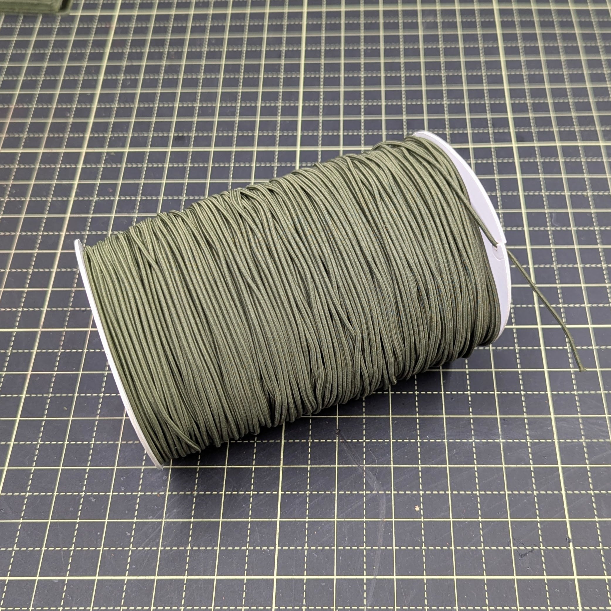 Spool of green thread on a grid background