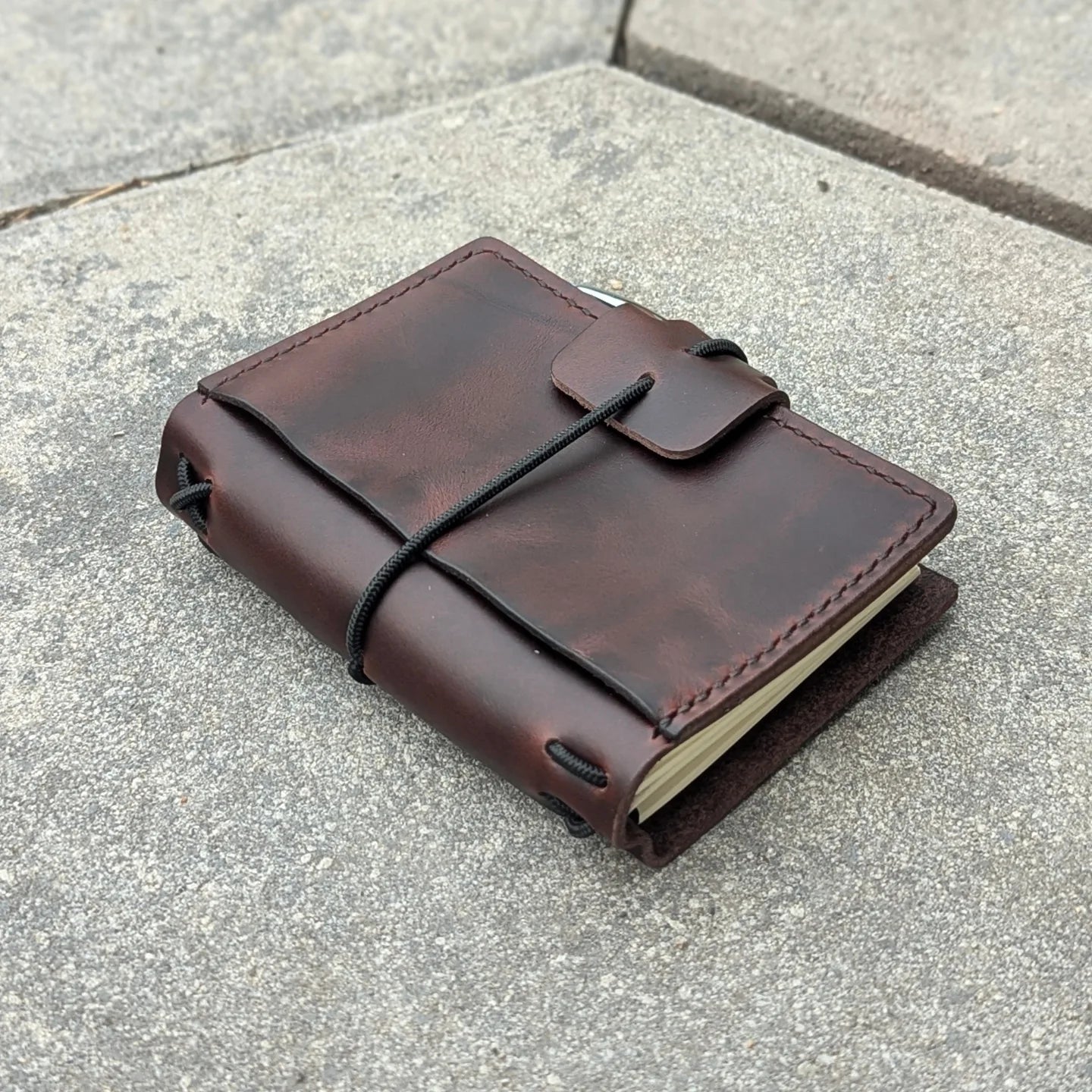 Brown leather notebook with string closure on a concrete surface