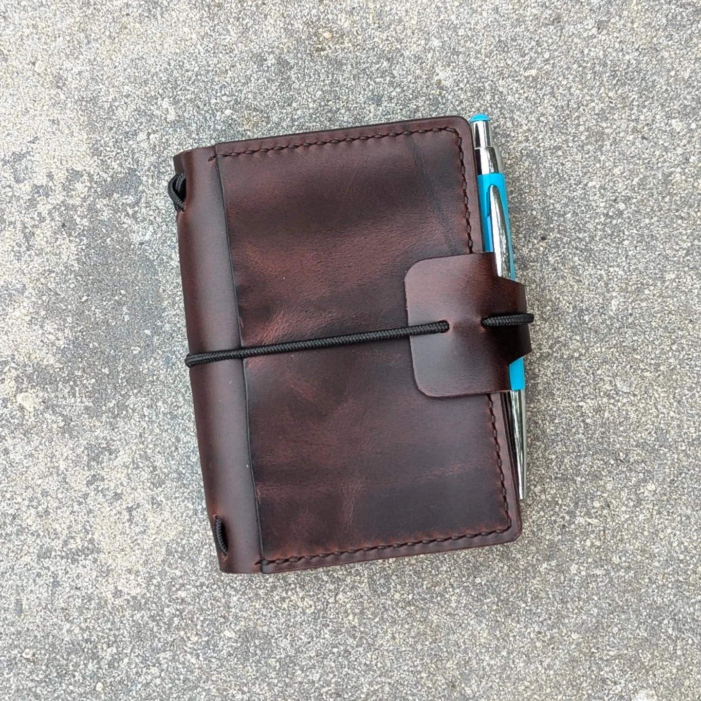 Brown leather notebook with a pen on a gray surface