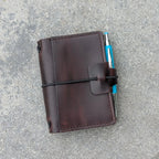 Brown leather notebook with a pen on a pavement background