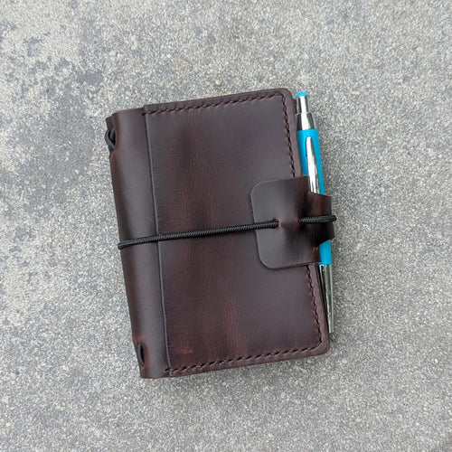 Brown leather notebook with a pen on a pavement background