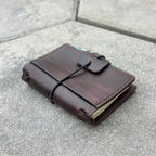 Brown leather notebook with string closure on a concrete surface