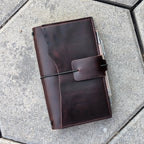 Brown leather notebook with pen on a gray pavement