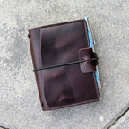 Brown leather notebook with a pen on a gray surface