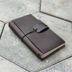 Brown leather notebook with string closure on a concrete surface