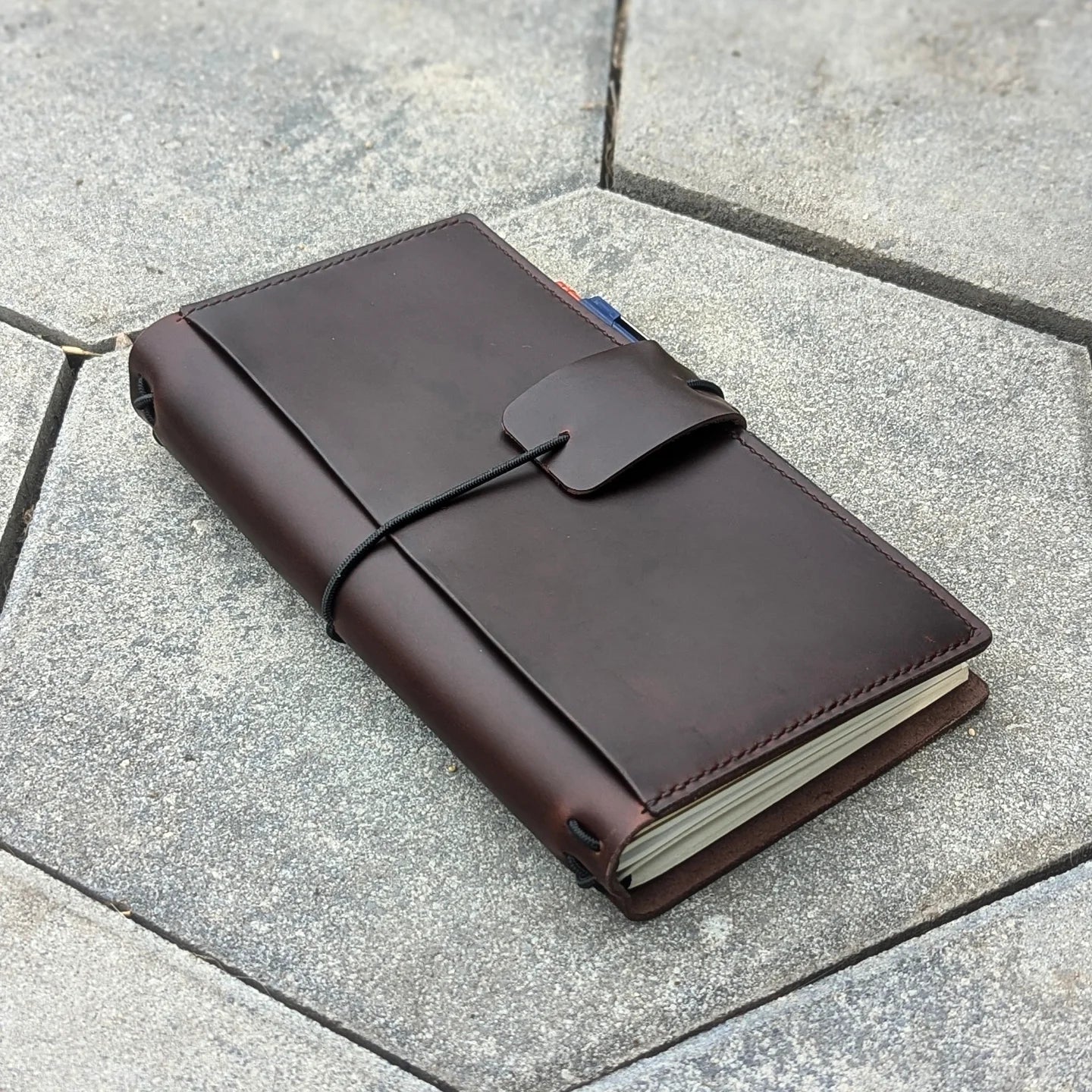 Brown leather notebook with string closure on a concrete surface