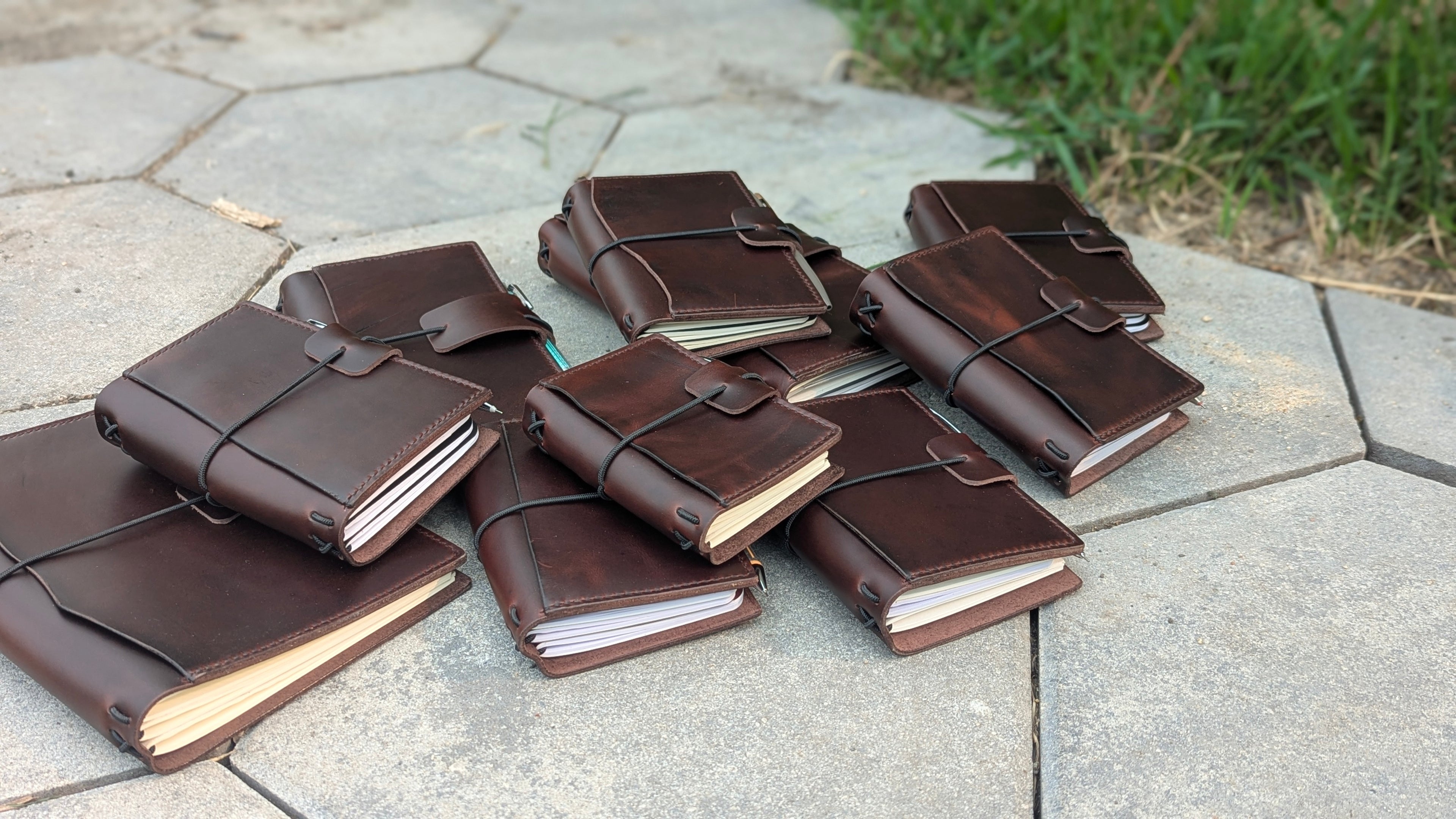 Collection of brown leather journals on a stone surface