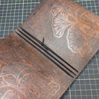 Interior of brown leather notebook cover showing three black elastic insert bands